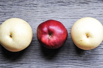 raw organic of 2 yellow Asian apple pears and 1 red apple in the middle on wooden table background