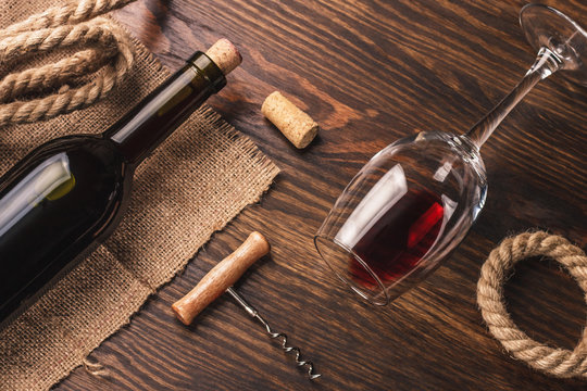 Glass with wine, bottle, corkscrew and burlap, top view