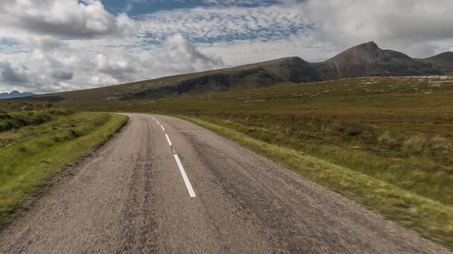 POV shot from a camera attached to the front of a vehicle driving through beautiful empty roads in the scottish highlands