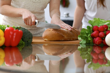 Close-up of human hands slicing bread in a kitchen. Friends having fun while cooking in the kitchen. Chef cook represent culinary masterclass