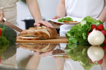 Close-up of human hands slicing bread in a kitchen. Friends having fun while cooking in the kitchen. Chef cook represent culinary masterclass
