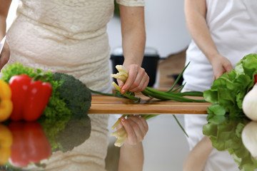 Close-up of  human hands  cooking in a kitchen. Friends having fun while preparing fresh salad. Vegetarian, healthy meal and friendship concept