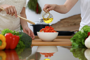 Close-up of  human hands  cooking in a kitchen. Friends having fun while preparing fresh salad. Vegetarian, healthy meal and friendship concept