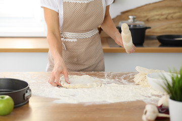 Female hands making dough for pizza or bread while using rolling pin. Baking concept