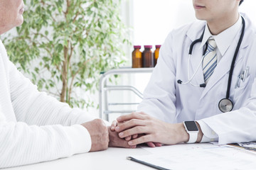 A young doctor holding a patient's hand