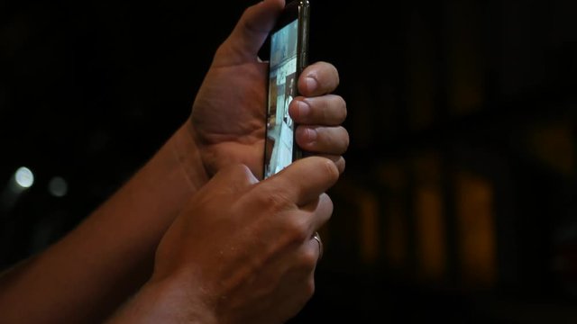 A man holds a phone and photographs in a dark room, a close-up. 3840x2160, 4K