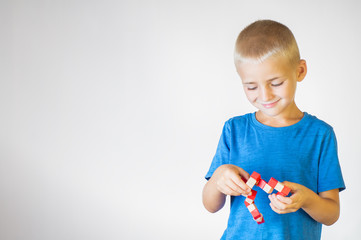 Boy with wooden logical toy. Child playing educational toys.