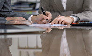 Group of business people and lawyers discussing contract while sitting at the table. Woman chief is taking pen for signing papers. Close-up of human hands at work. Meeting or negotiation concept in