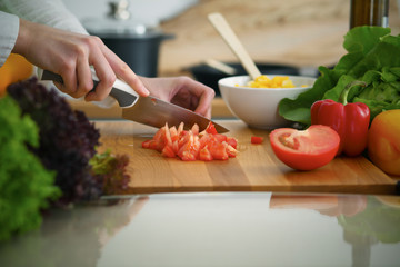 Closeup of human hands cooking vegetables salad in kitchen on the glass  table with reflection