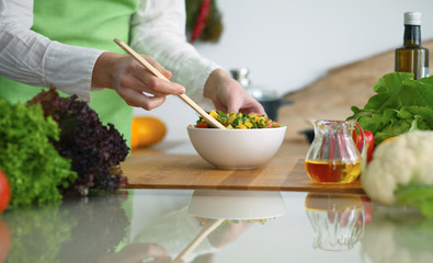 Closeup of human hands cooking vegetables salad in kitchen on the glass  table with reflection