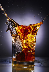 splash of whiskey with ice.Grey background.Concept alcohol splash