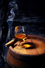 Cognac and Cigar on old oak barrel.Blue stone background
