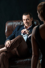 Fototapeta premium The artist or mature man wearing suit in a classical retro fashion style. The woman standing near