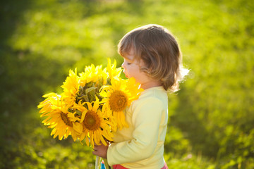 Happy child with bouquet of beautiful sunflowers.
