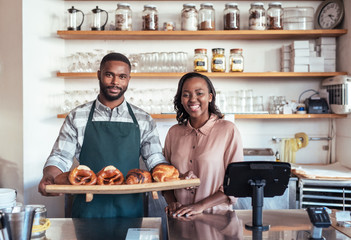 Smiling African entrepreneurs with baked goods behind their bakery counter