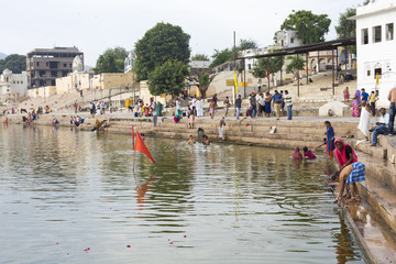 Hindu devotees pilgrims bathing in sacred Puskhar lake (Sagar) on ghats of Pushkar, Rajasthan. Pushkar is holy city for Hinduists and famous for many Hindu temples.