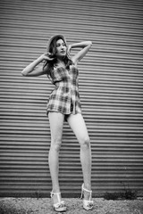 Amazing long legs with hig heels girl wear on hat against shutter.