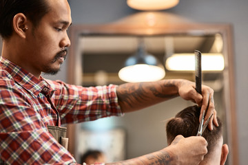 Concentrated barber doing a haircut for his regular client