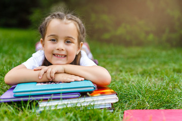 little girl lies on the grass with a book in the park