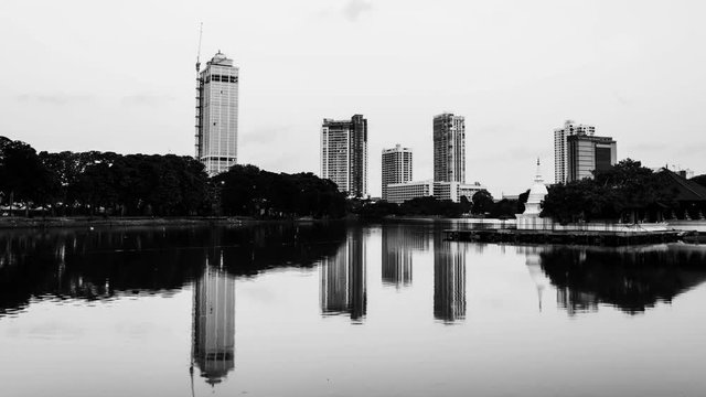 Sri Lanka. View of Beira Lake in Colombo, Sri Lanka with buddhist temple and illuminated modern buildings at sunset. Night to day time-lapse. Black and white