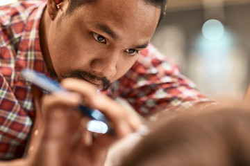 Serious professional thai barber shaving the beard