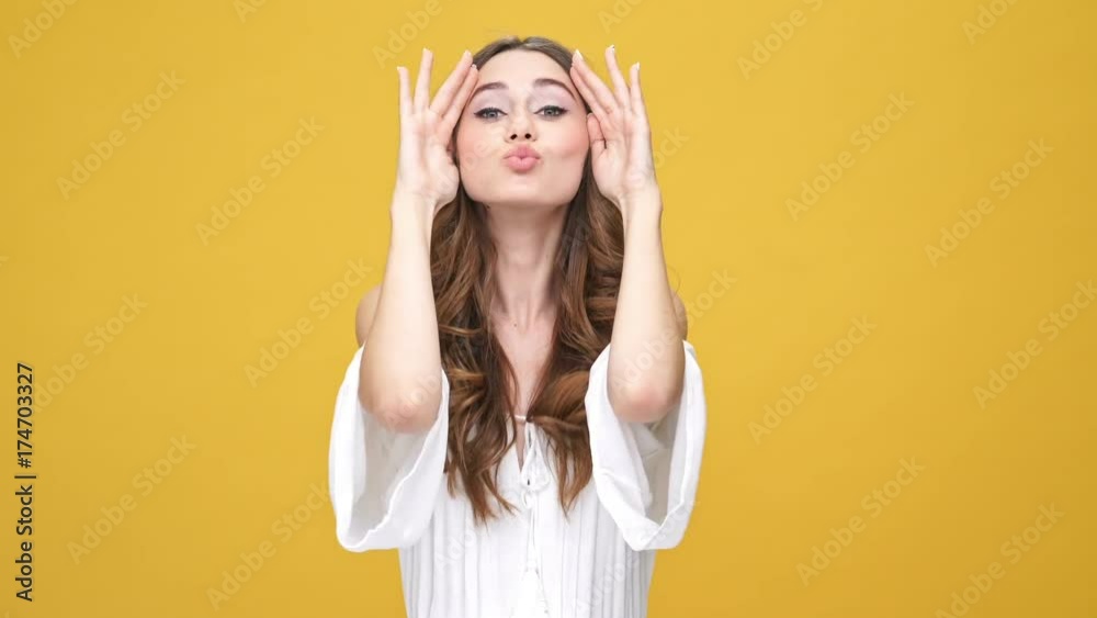 Wall mural Happy brunette woman in dress covering her face and showing different facial expressions at the camera over orange background