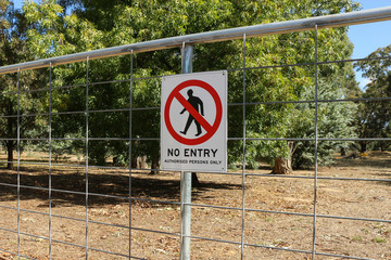 red, black and white No Entry - Authorised Persons Only sign on a gate