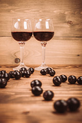 Two glasses of red wine and grapes on wooden table