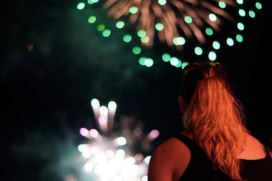 A young woman watches fireworks