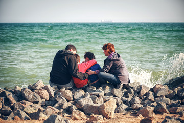 Happy family sitting on stony beach