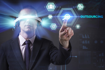 Business, Technology, Internet and network concept. Young businessman working in virtual reality glasses sees the inscription: Outsourcing