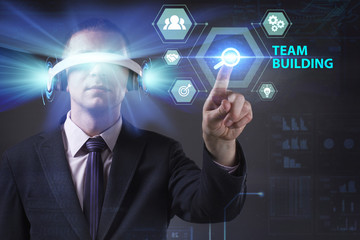 Business, Technology, Internet and network concept. Young businessman working in virtual reality glasses sees the inscription: Team building
