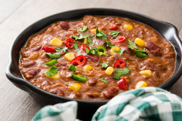 Traditional mexican tex mex chili con carne in a frying pan on wooden table