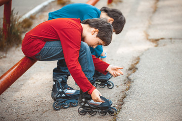 boys lace his roller skate sitting on the sidewalk