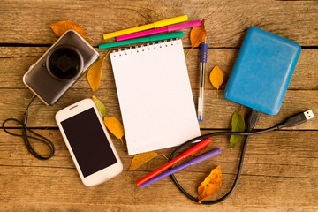 Open white empty notepad  with colorful felt-tip pens, smartphone, camera and blue hard disk on the table