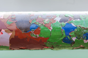 Fototapeta na wymiar Peeling paint on a metal bar. Multiple layers of colored paint.