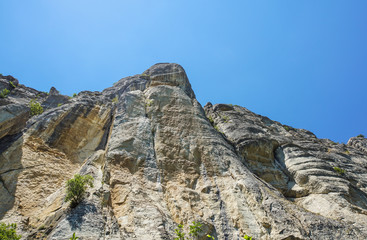 rocky wall of a mountain stretching up to the blue sky