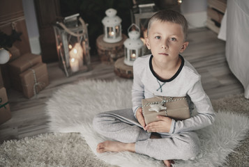Fototapeta na wymiar Boy with a gift squatting on rug at home