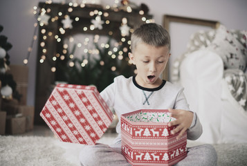 Boy opening christmas gift at home  .