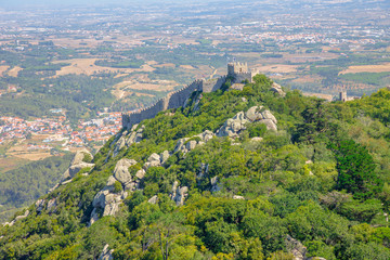 Fototapeta na wymiar Aerial view of Castle of the Moors and Sintra valley from Pena National Palace. Moorish fortress or Castelo dos Mouros is medieval castle and Unesco Heritage on top of a hill above Sintra, Portugal.