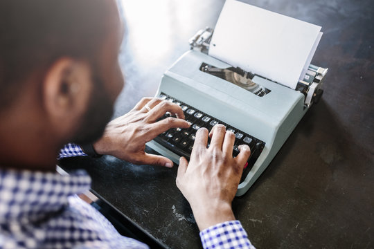 Close-up of man at desk using typewriter