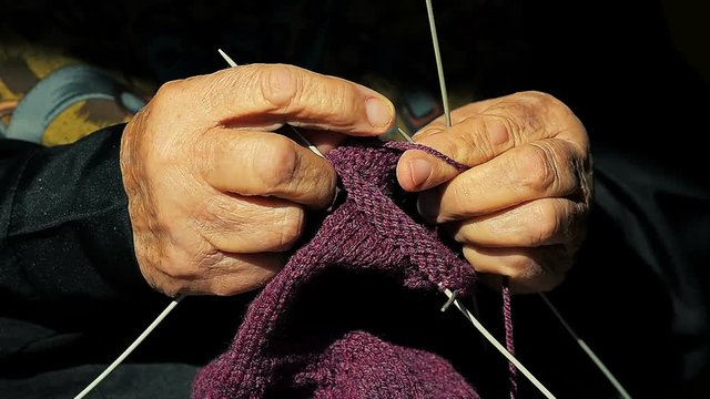 Close-up of a hands of old grandmother knitting warm socks for her grandchildren.