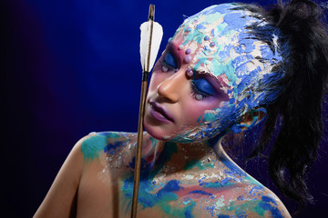 Mysterios girl with closed eyes on the deep-blue background. Model wears bright mysterious make-up,...