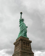 Statue of liberty seen from the front with a grey and cloudy sky as background in Manhattan, New York City.