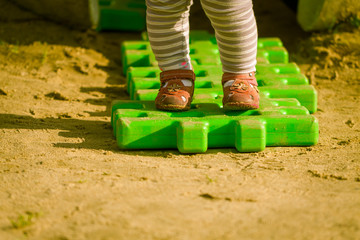 Walking girl children by green plastic puzzle.