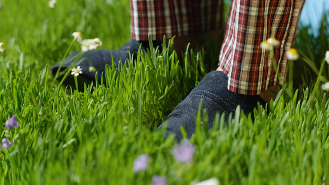 Man stands on the grass in Slippers. Male feet in sneakers on the grass