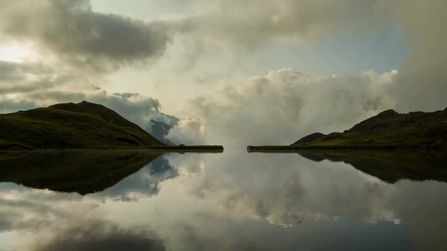 Time lapse clouds reflecting like Rorschach test  in swiss mountain lake Bachalpsee with Schreckhorn massif background near Grindelwald Switzerland Alps