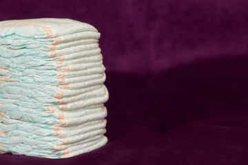 Stack of diapers or nappies on purple background
