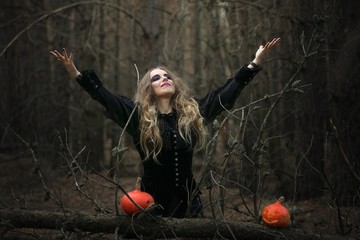 Halloween. beautiful witch girl in a black dress in the forest.