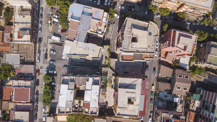 Vista aerea perpendicolare dei tetti di alti palazzi adibiti ad uso residenziale in una grande città italiana. Le automobili e le persone dall'alto sembrano molto piccoli. - obrazy, fototapety, plakaty